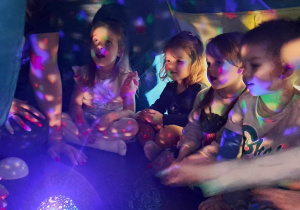 Dzieci w namiocie oglądają gwiazdy wyświetlane przez projektor