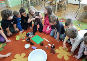 Zabawy z magnesem. Dzieci siedzą na dywanie. Na środku leżą przedmioty z różnego tworzywa. Dzieci będą sprawdzać które z nich przyciągnie magnes.