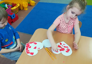Dzieci wyklejają papierowe serca.
