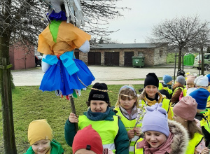 Dzieci ustawione w parach na placu przedszkolnym. Trzymają Marzannę.