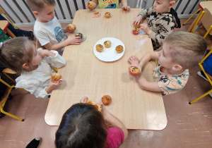Dzieci w czasie słodkiego poczęstunku siedzą przy stoliku