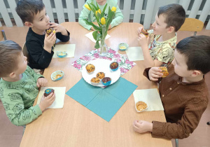 Dzieci podczas poczęstunku przy stolikach.
