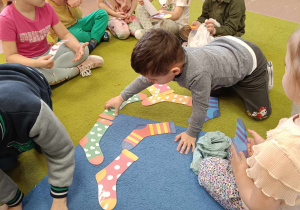 Dzieci układają papierowe skarpety na dywanie
