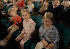 Dzieci siedzą na widowni w oczekiwaniu na spektakl.