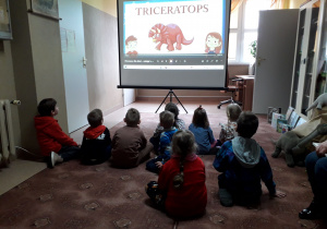 Dzieci oglądają film o dinozaurach.