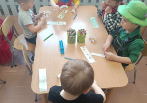 Dzieci z grupy 3-4 latków siedzą przy stolikach i robią zakładkę do książki