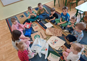 Dzieci siedzą w kole i ogladają rodzaje toreb na zakupy.