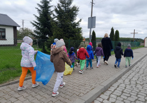 Dzieci porządkują teren wokół przedszkola.