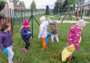 Dzieci porządkują teren wokół przedszkola.