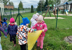 Dzieci porządkują teren wokół przedszkola.