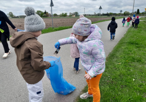 Dzieci porządkują teren wokół przedszkola.