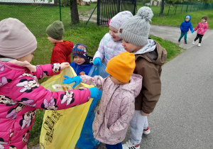 Dzieci porządkują teren wokół przedszkola.