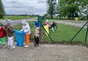 Dzieci porządkują teren wokół przedszkola.