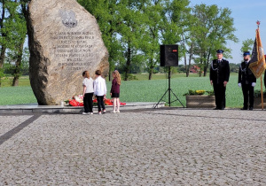 Delegacja dzieci składa wiązankę kwiatów pod obeliskiem.