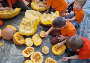 Dzieci siedzą i wydrążają pestki z dyni.