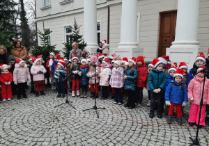 Dzieci stoją przed Pałacem w Starym Gostkowie i śpiewają piosenkę