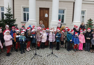 Dzieci stoją przed Pałacem w Starym Gostkowie i śpiewają świąteczne piosenki.