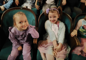 Dzieci siedzą na fotelach w teatrze i czekają na rozpoczęcie spektaklu