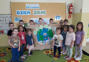 Dzieci prezentują plakat wykonany z okazji Dnia Ziemi.