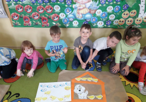 Grupa dzieci prezentuje wykonany domek z pasków dla kurczaczków i przyjaciela Pimpusia Kurki Szóstki.