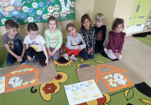 Grupa dzieci prezentuje wykonany domek z pasków dla kurczaczków i przyjaciela Pimpusia Kurki Szóstki.