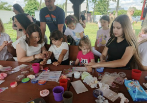 Dzieci z rodzicami w kąciku malowania twarzy i robienia tatuaży.