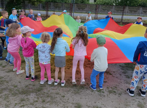 Dzieci w ogrodzie przedszkolnym z chustą animacyjną