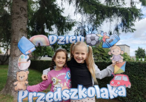 Dziewczynki pozują do zdjęcia w fotobudce.