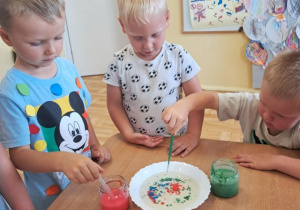 Chłopcy podczas eksperymentu z kolorowymi kropkami na talerzu.