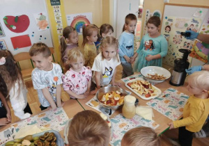 Przedszkolaki obserwują proces wyciskania soku z owoców.