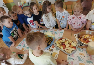 Przedszkolaki obserwują proces wyciskania soku z owoców.