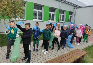 Dzieci z grupy 5-6 latków stoją przed przedszkolem z rękawiczkami i workami na śmieci przygotowują się do akcji