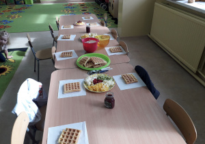 Na stolikach znajdują się produkty potrzebne do przygotowania owocowych gofrów i musu owocowego.