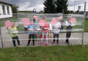Grupa dzieci maluje swoje portrety w plenerowej strefie kreatywności.