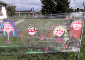 Namalowane portrety dzieci w plenerowej strefie kreatywności.