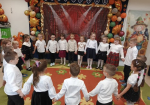 Przedszkolaki stoją w kole i prezentują zabawę.