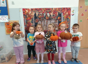 Dzieci pozują do zdjęcia z dyniami na tle dekoracji