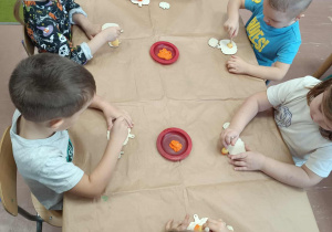 Dzieci przy stoliku malują dynię.