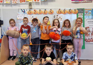 Dzieci z grupy 5-6 latków w grupie pozują z dyniami
