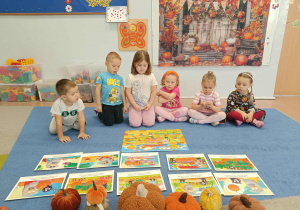 Dzieci oglądają historyjkę obrazkową o dyniach.