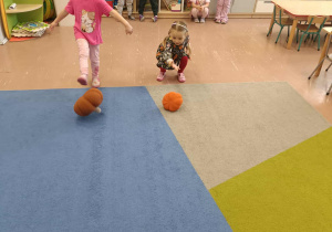 Dzieci toczą pluszowe dynie.