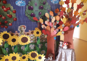 Jesienny kącik w przedszkolu ozdobiony słonecznikami i jesiennymi drzewami- prace wykonane przez dzieci.