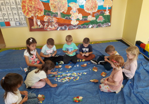 Dzieci na dywanie wykonują portret jeżyka Roro, bohatera zajęcia "Metamorfoza serduszka" realizowanego w ramach Tygodnia Budowania Relacji.