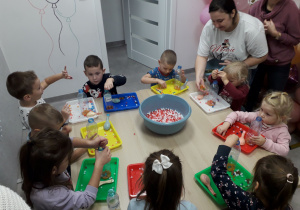 Sala zabaw. Dzieci przy stoliku wykonują gniotka.