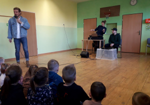 Dzieci podczas audycji muzycznej słuchają prowadzącego audycję.