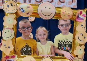 Przedszkolaki pozują do zdjęcia w fotoramce.