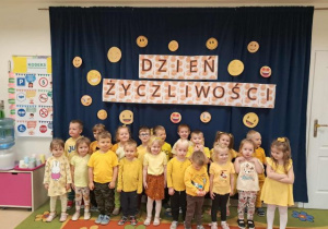 Dzieci z grupy 3,4-latków ubrane na żółto pozują do zdjęcia grupowego.