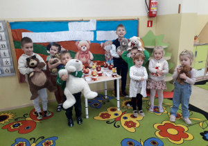 Dzieci ze swoimi pluszowymi misiami pozują na tle dekoracji Święto Pluszowego Misia.