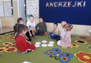 Dzieci na dywanie i andrzejkowa wróżba z talerzykami.