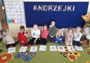 Dzieci na dywanie prezentują swoje znaki zodiaku, trzymając w ręku ciasteczko z wróżbą.